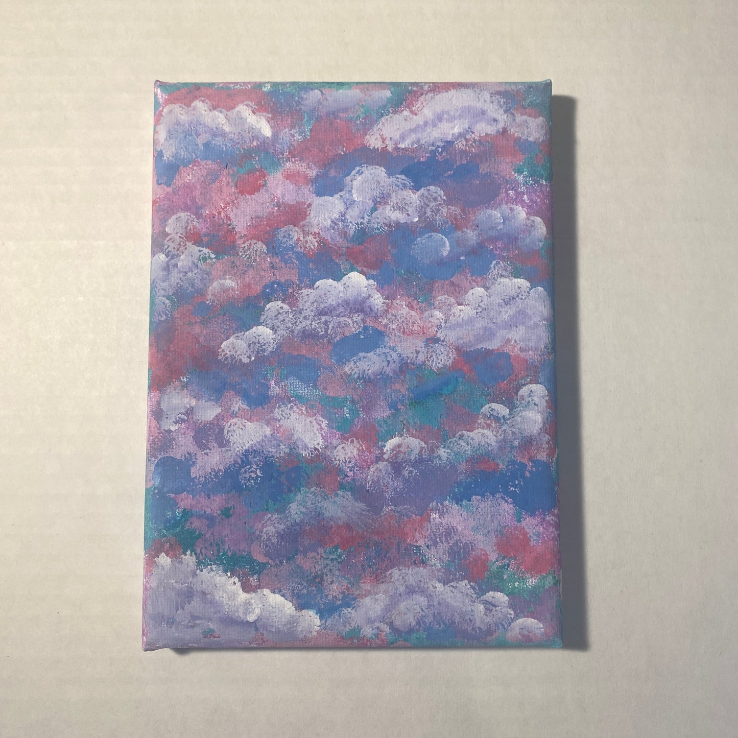 Layers of clouds are created with a sponge brush in colors ranging from white, purple, light and hot pink, light blue, and turquoise.
